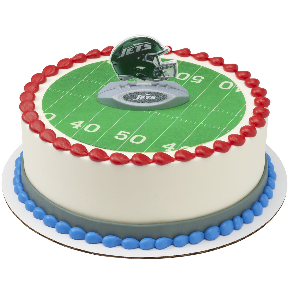A round cake decorated with a green football field print, red piped border, blue base trim, and a New York Jetshelmet topper on top. The cake is photographed on a plain white background.