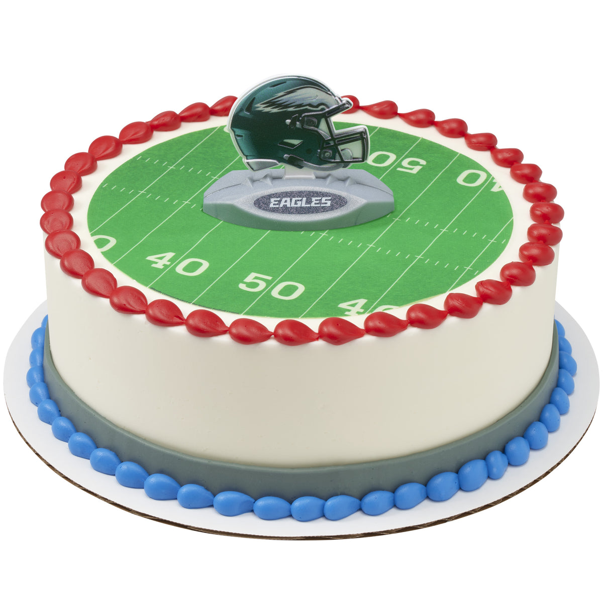 A round cake decorated with a Philadelphia Eagles football theme, featuring a green yard line design, red and blue piped borders, and an Eagles helmet topper on a white background.