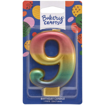 Packaged metallic rainbow number 9 birthday candle with a pink-to-gold-to-green-to-blue gradient and a gold base, on a blue Bakery Crafts card.