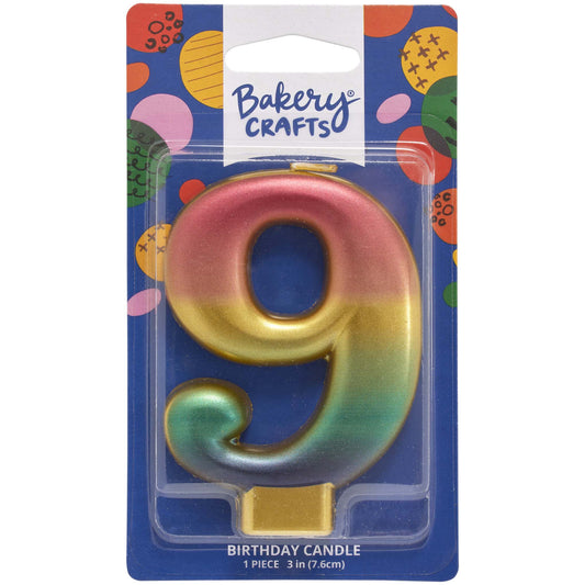 Packaged metallic rainbow number 9 birthday candle with a pink-to-gold-to-green-to-blue gradient and a gold base, on a blue Bakery Crafts card.