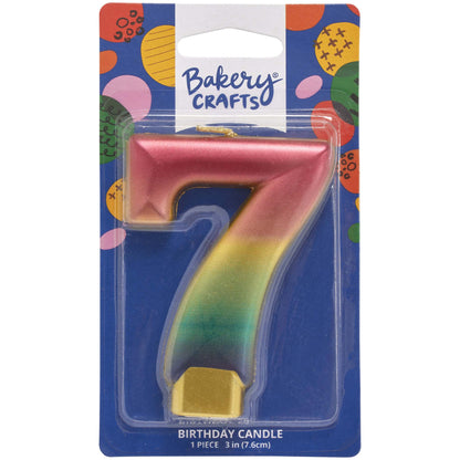 Packaged metallic rainbow number 7 birthday candle with a pink-to-gold-to-green-to-blue gradient and a gold base, on a blue Bakery Crafts card.