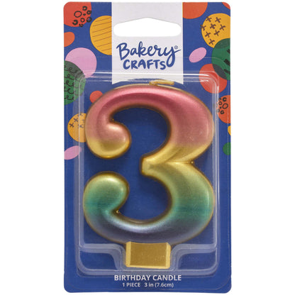 Packaged metallic rainbow number 3 birthday candle with a pink-to-gold-to-green-to-blue gradient and a gold base, on a blue Bakery Crafts card.