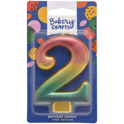 Packaged metallic rainbow number 2 birthday candle with a pink-to-gold-to-green-to-blue gradient and a gold base, on a blue Bakery Crafts card.