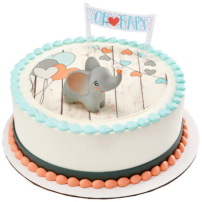 Round baby shower cake with heart and balloon design, decorated with a smiling gray elephant topper and a “Oh Baby” banner.