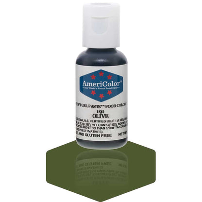 A bottle of AmeriColor Olive soft gel paste food coloring with a white cap and blue label featuring red stars, standing on a deep olive green reflective surface that mirrors the bottle.