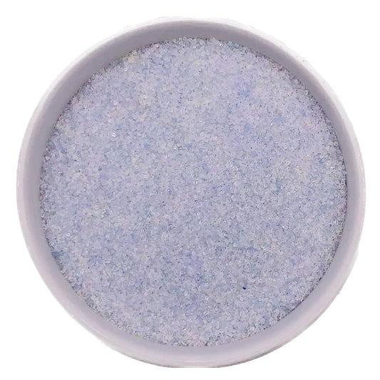 Top-down view of a white bowl filled with opal fine sanding sugar, showing very pale iridescent crystals with a soft pearly shimmer.