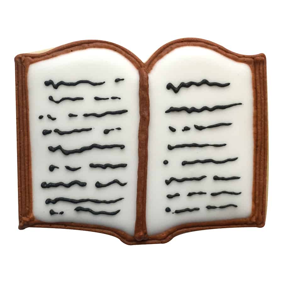 Decorated book-shaped cookie with white icing pages and black icing text details.