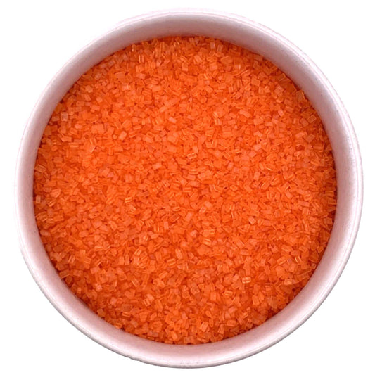 Top-down view of a white bowl filled with orange coarse sanding sugar crystals, showing bright orange, chunky granules packed closely together.