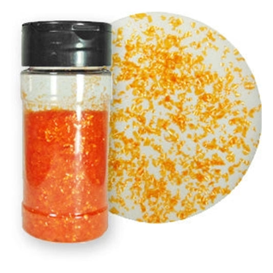 Clear shaker bottle filled with bright orange edible glitter flakes beside a white sample surface scattered with shimmering orange flakes.