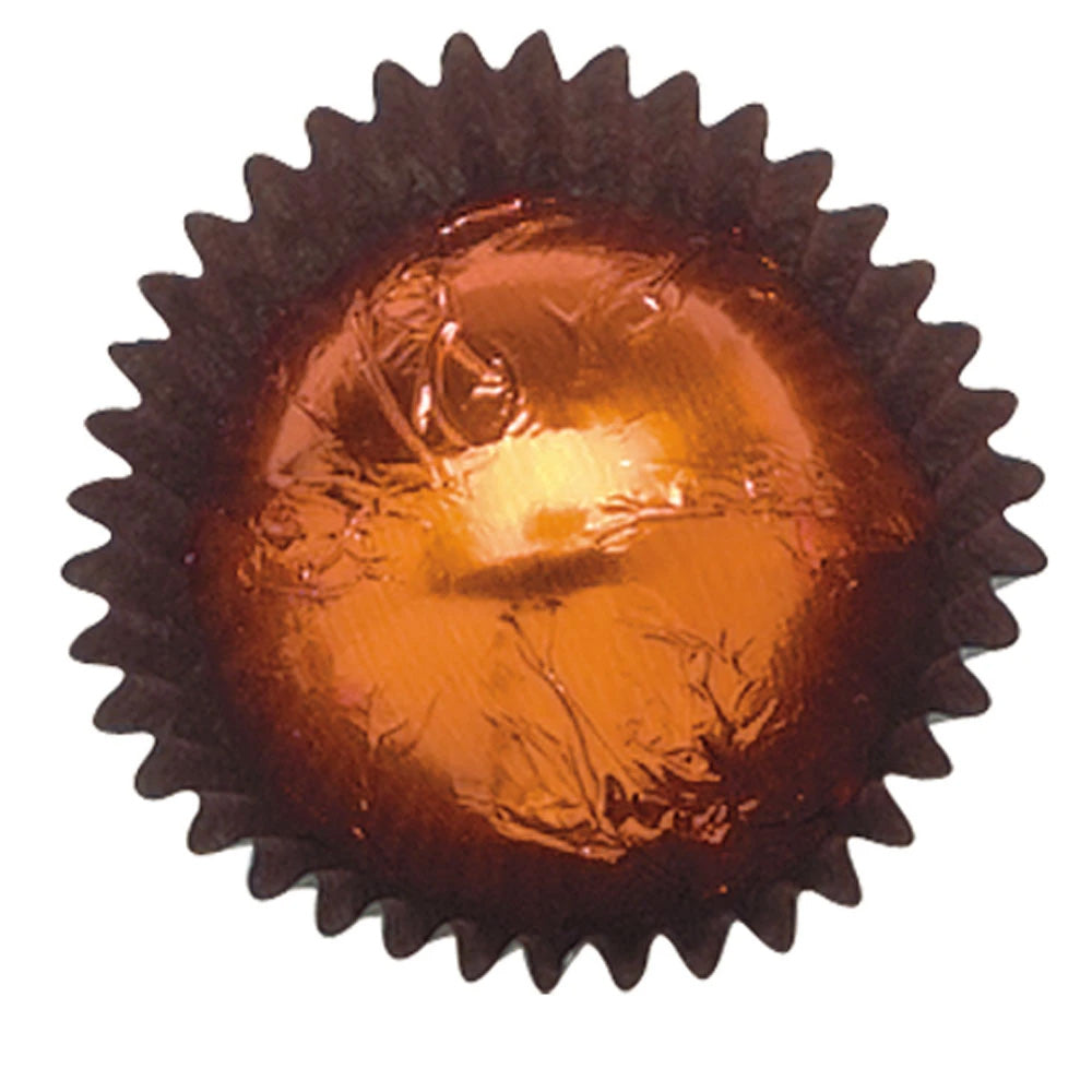 Close-up of a copper foil-wrapped chocolate in a dark brown paper candy cup, showing warm metallic copper foil with crinkled edges.