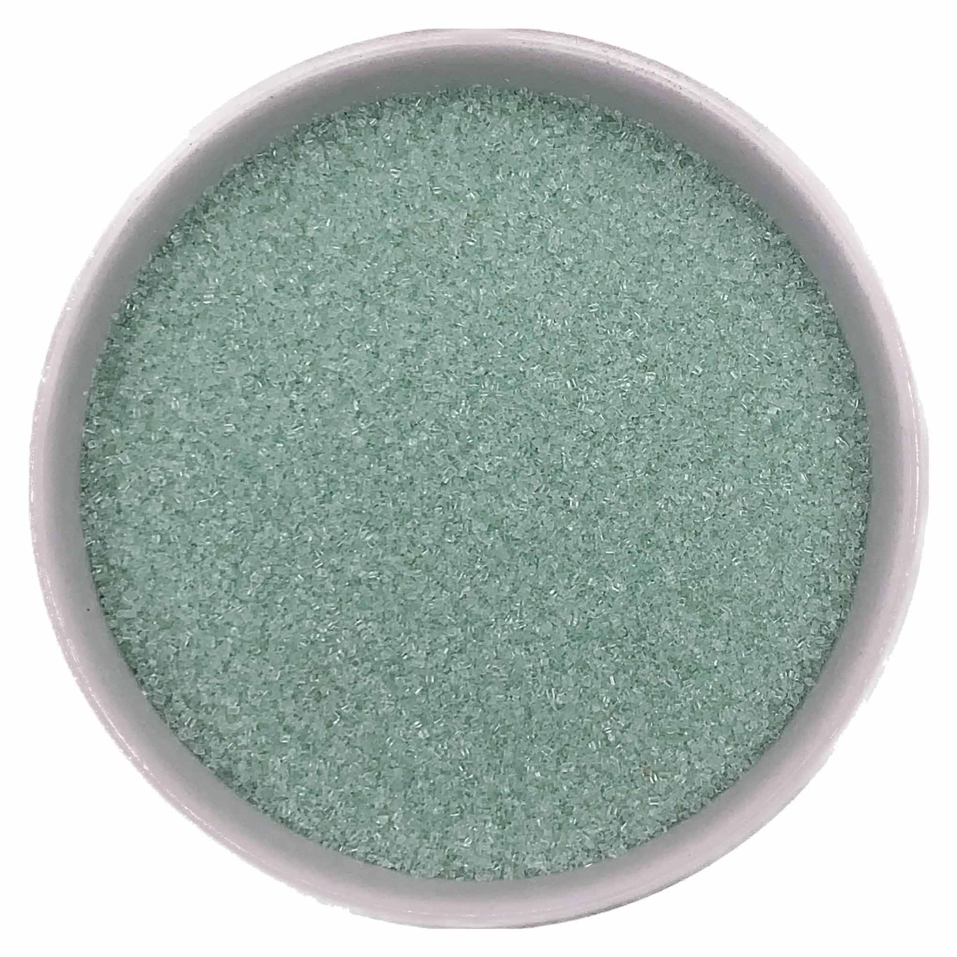 Top-down view of a white bowl filled with pastel green fine sanding sugar, showing tiny pale mint-green crystals with a soft shimmering texture.