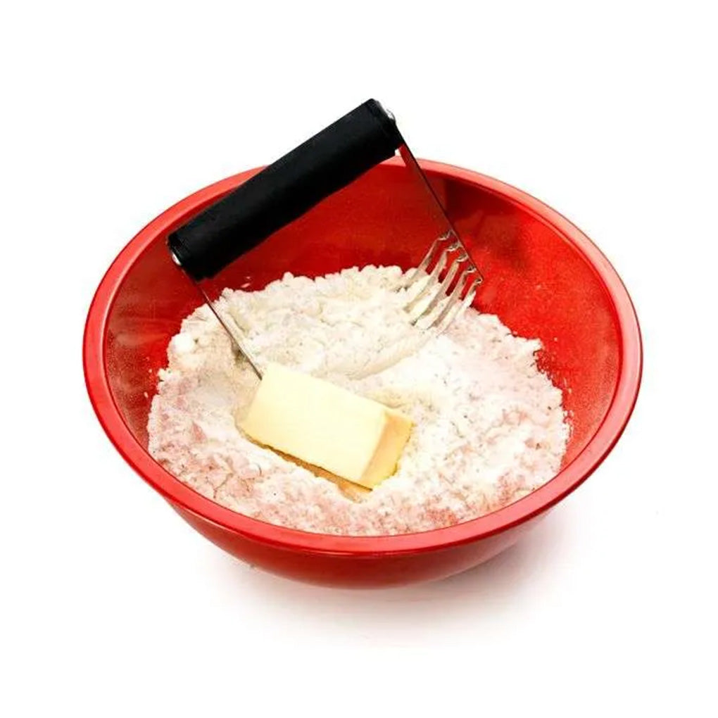 Pastry blender cutting a stick of butter into flour inside a red mixing bowl, showing the black handle and stainless steel blades in use.