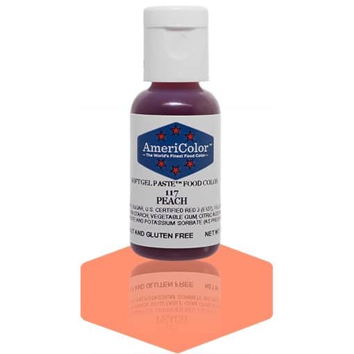 A bottle of AmeriColor Peach soft gel paste food coloring with a white cap and blue label featuring red stars, standing on a glossy peach-colored surface that reflects the bottle.