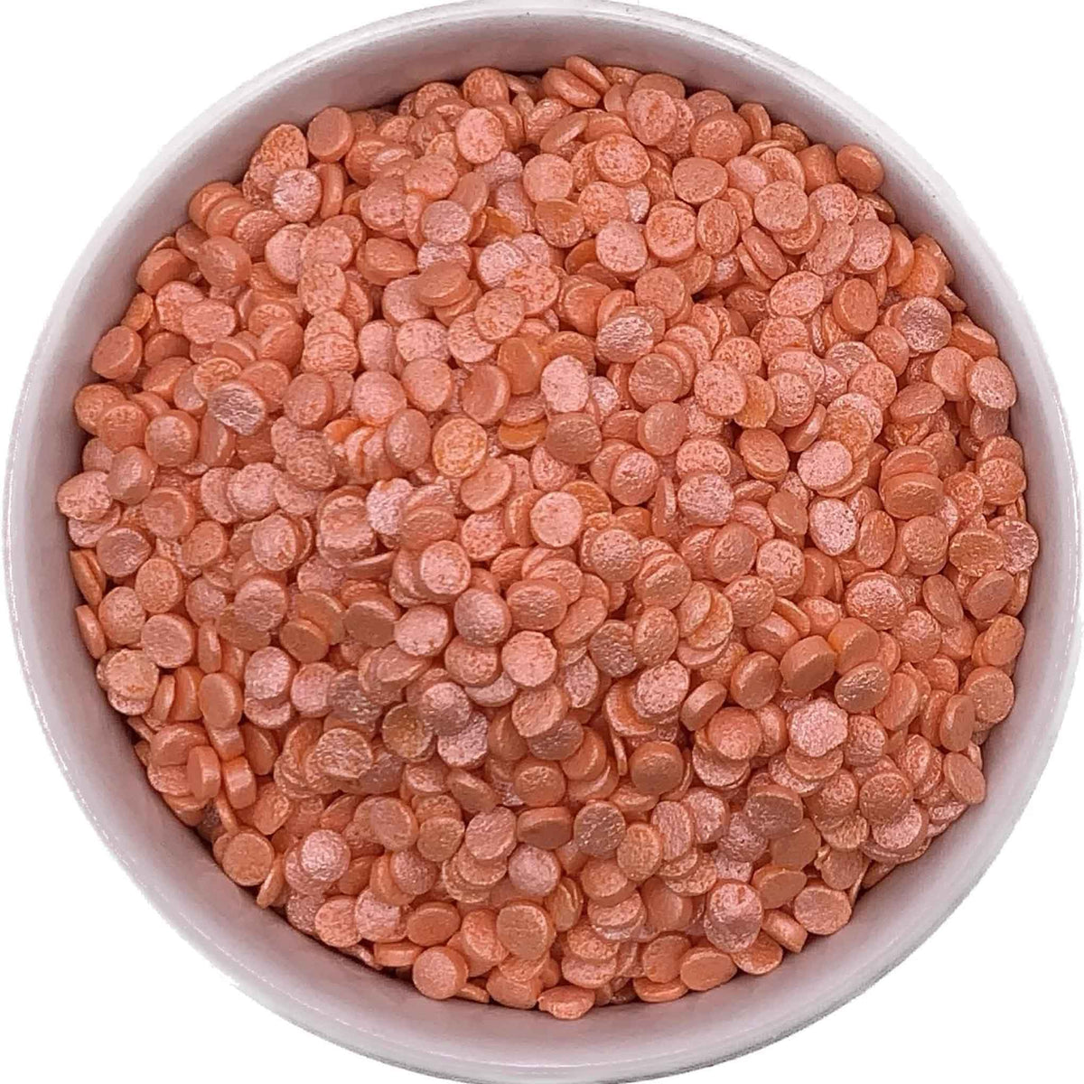 Peach Pearl Confetti Quinn Sprinkles in a white bowl, showing their small, flat, round shape and pearly finish