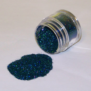 Jar of deep teal peacock Galaxy Glitter Dust tipped over, sparkling with rich green-blue hues and subtle iridescent highlights.