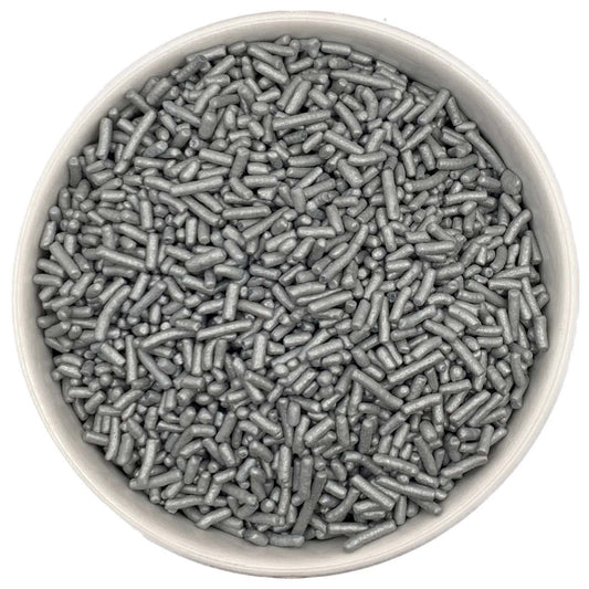 Top-down close-up of a white round container filled with pearlized silver jimmies sprinkles, showing metallic sheen on small rod-shaped pieces.