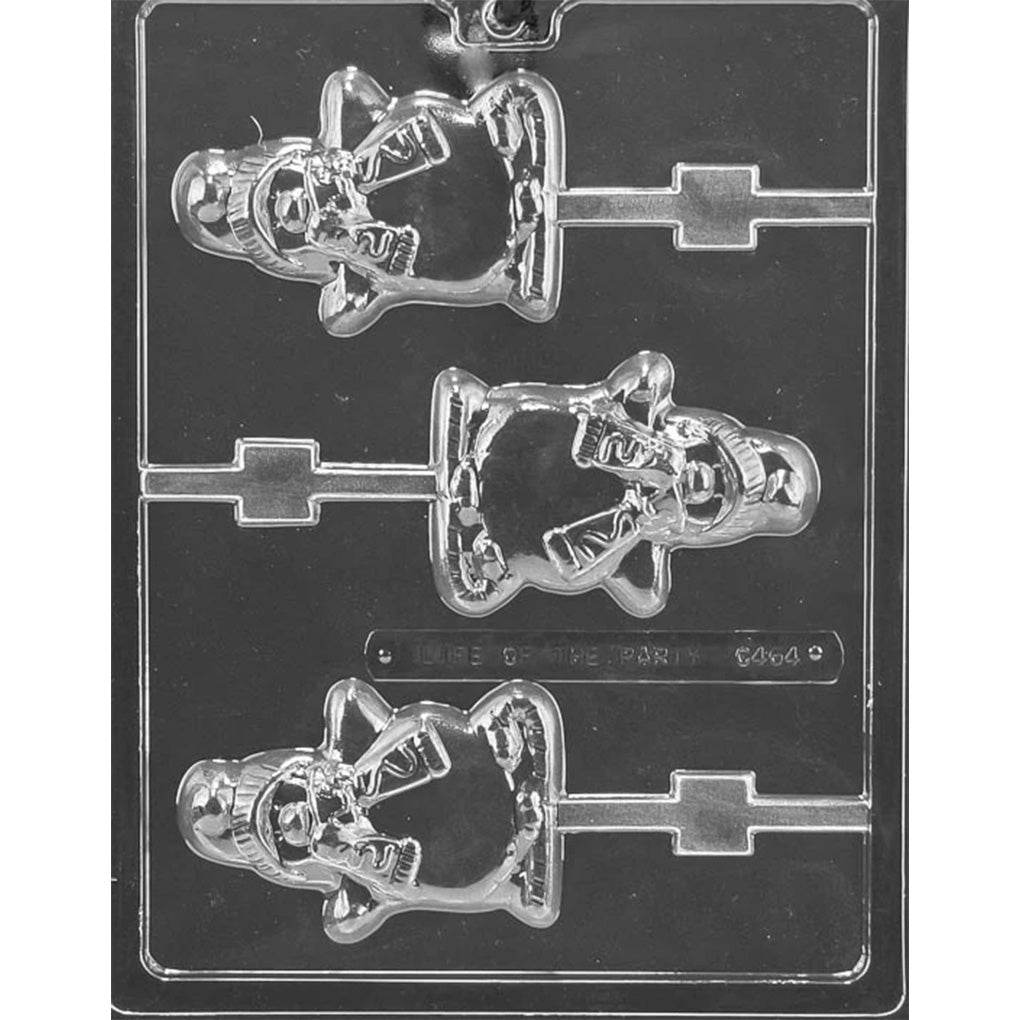 Clear plastic chocolate lollipop mold with three penguin cavities, each penguin wearing a winter hat and scarf with raised details and a stick channel, on a dark background.