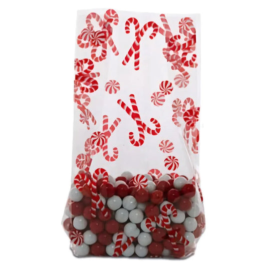 Clear cellophane treat bag printed with red candy canes and peppermint swirl candies, shown filled with red and white round candies and standing upright.