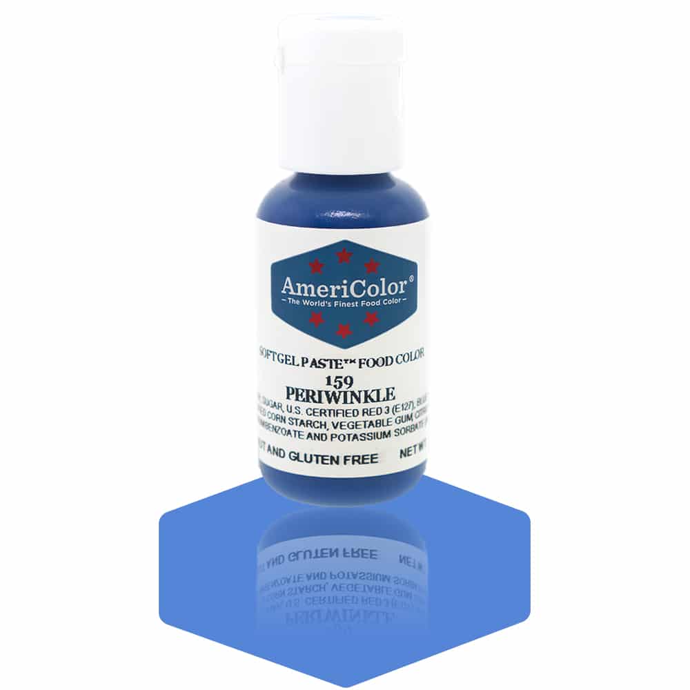 A bottle of AmeriColor Periwinkle soft gel paste food coloring with a white cap and blue label adorned with red stars, positioned on a soft periwinkle blue reflective surface with the bottle’s reflection clearly visible.