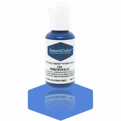 A bottle of AmeriColor Periwinkle soft gel paste food coloring with a white cap and blue label adorned with red stars, positioned on a soft periwinkle blue reflective surface with the bottle’s reflection clearly visible.