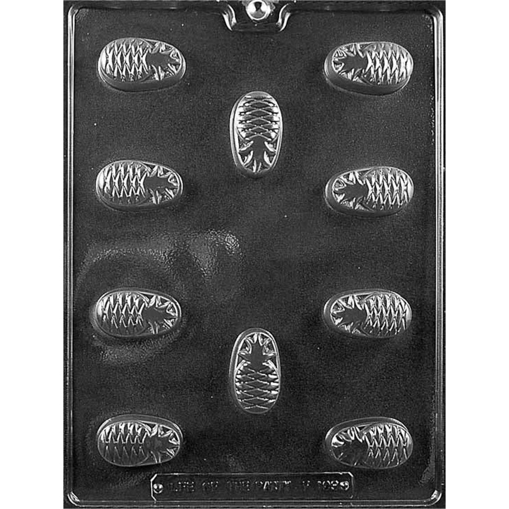Clear plastic chocolate mold with oval pineapple-textured cavities for making filled chocolates, shown on a black background.