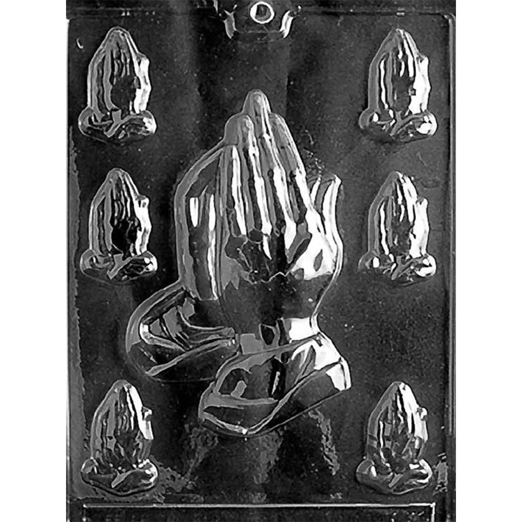 Clear Assorted Praying Hands Chocolate Mold photographed against a black background with 7 cavities, including 1 large praying hands design and 6 smaller matching designs.