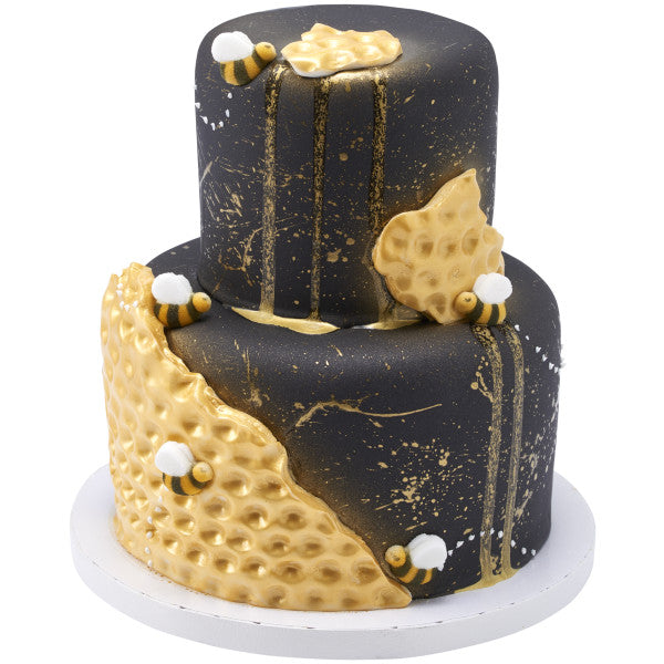 Two-tier black and gold honeycomb-themed cake with pressed sugar bee decorations