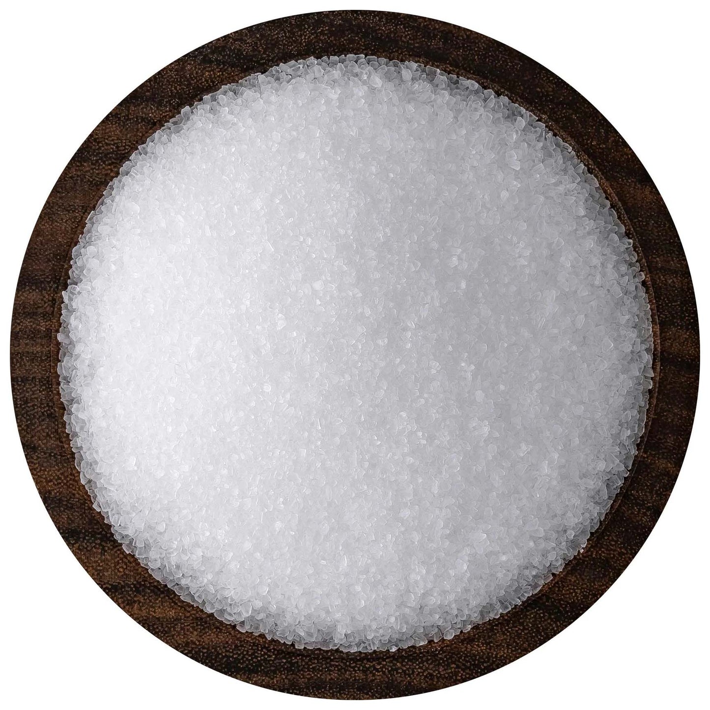Overhead view of coarse white sea salt crystals piled in a round dark wooden bowl against a white background.