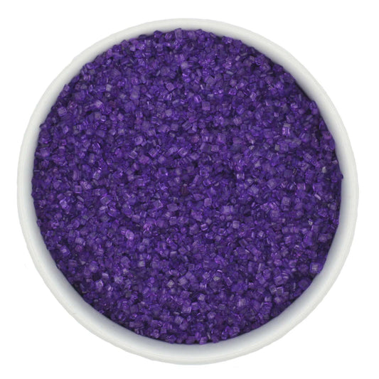 Top-down view of a white bowl filled with deep purple coarse sanding sugar crystals, showing chunky sparkling granules and a saturated violet color.