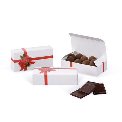 Red ribbon and holly candy boxes shown closed and open on a white background, with chocolate truffles inside the open box and chocolate squares in front.