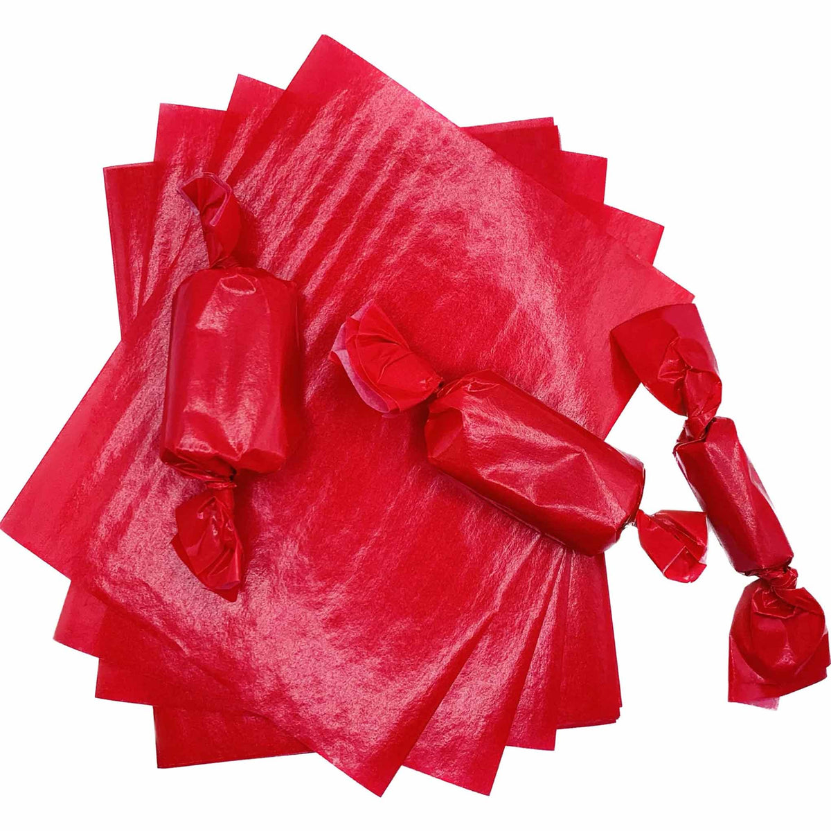 Stack of red 4" x 5" wax caramel wrappers with three rectangular caramel pieces individually wrapped and twisted at both ends.