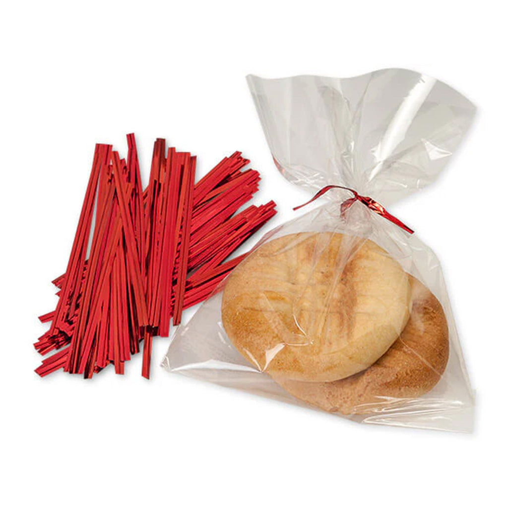 Red metallic twist ties beside a clear cellophane treat bag tied at the top, holding two round cookies on a white background.