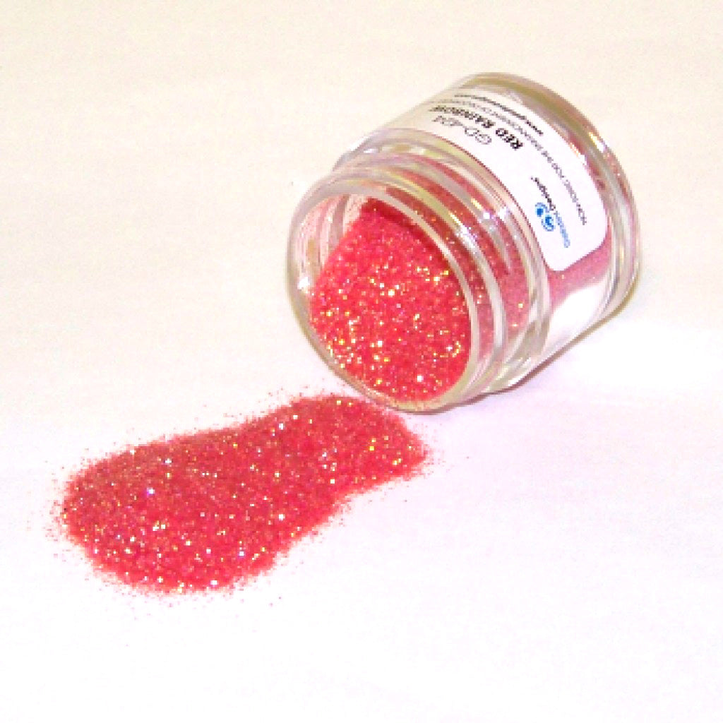 Small clear jar of Red Rainbow Galaxy Glitter Dust tipped on its side with sparkling red iridescent glitter spilled onto a white background.
