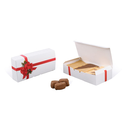 White holiday candy box with red ribbon and holly bow design, shown closed and open with assorted fudge inside.
