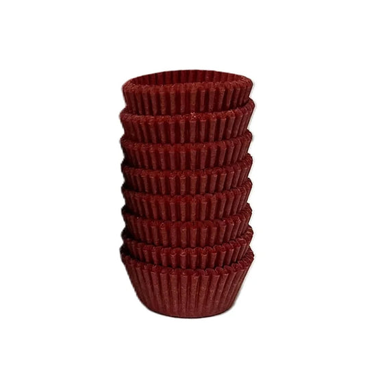 Stack of red #5 candy cups with fluted sides on a white background.