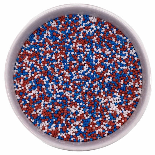 Bowl of red, white, and blue nonpareil sprinkles (All American mix) on a white background.