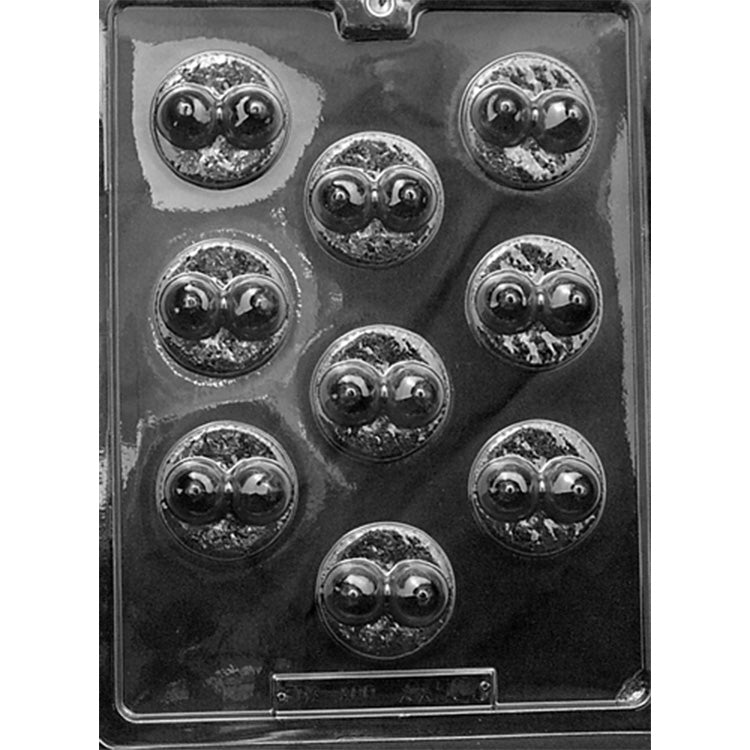 Clear plastic chocolate mint mold photographed against a dark background, with nine round cavities featuring raised pairs of breasts and textured circular borders.