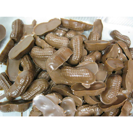 Close-up of milk chocolate peanut candies showing peanut shapes and broken chocolate pieces in a tray.