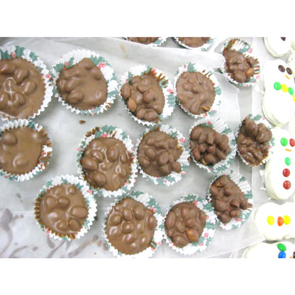 Assorted chocolate peanut clusters in small paper candy cups on a parchment-lined tray, photographed from above.