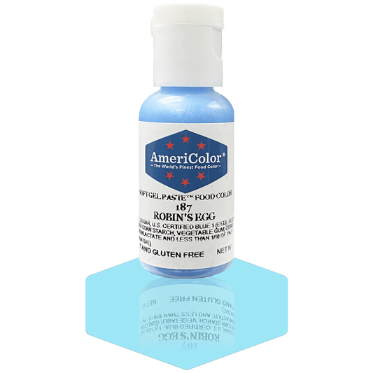 A bottle of AmeriColor Robin's Egg soft gel paste food coloring with a white cap, blue label, and red stars, positioned on a soft robin's egg blue reflective surface with the bottle’s reflection clearly visible.