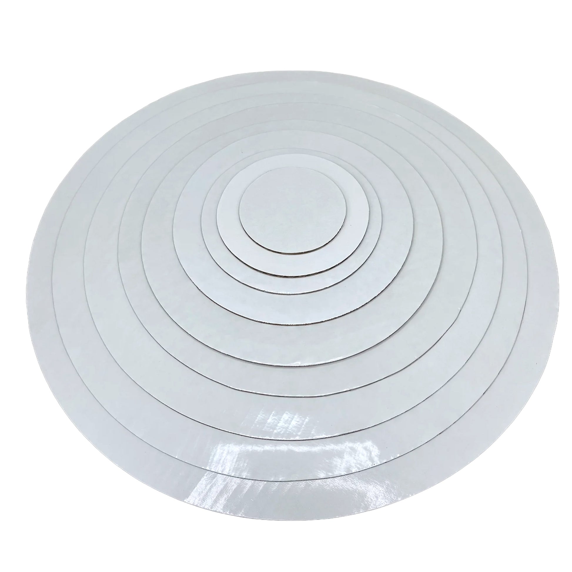 Stack of white round wax-coated cardboard cake boards in assorted sizes on a white background.