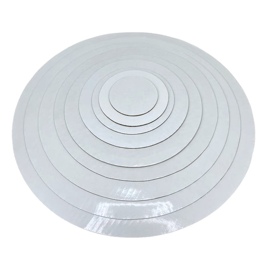 Stack of white round wax-coated cardboard cake boards in assorted sizes on a white background.