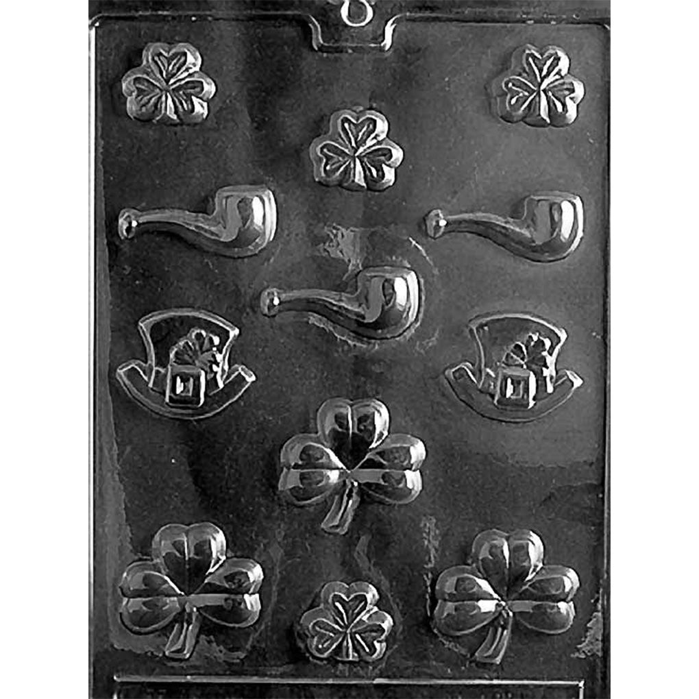 St. Patrick’s Day assortment chocolate mold with multiple small cavities shaped like shamrocks, curved pipes, and leprechaun hats, plus several larger clover shapes, shown in clear plastic.