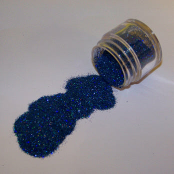 Deep sapphire-toned Galaxy Glitter Dust poured from a jar, shimmering with fine hints of green and blue sparkle.