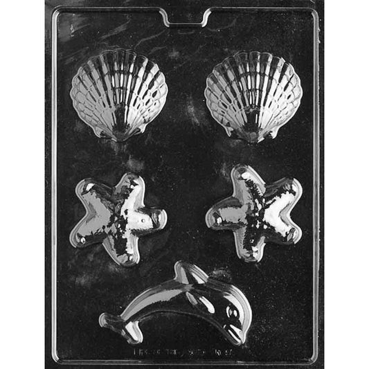 Clear plastic chocolate mold with five cavities: two scallop shells at the top, two starfish in the middle, and one dolphin at the bottom, shown on a dark background.