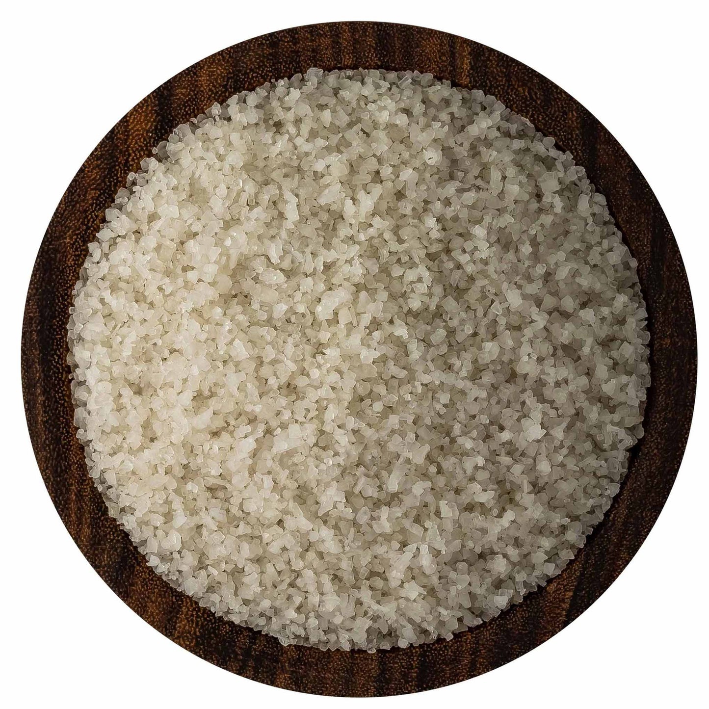 Overhead view of fine French grey sea salt crystals in a round dark wooden bowl on a white background, showing pale grey-beige grains.