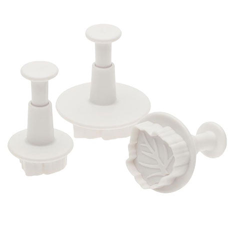 Set of three white plastic leaf sugar paste cutters with embossed detailing and spring-loaded plungers for precise fondant and gum paste decorations.