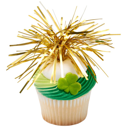 Cupcake with green swirled frosting topped with a gold tinsel spray and a green shamrock sugar decoration, shown on a white background.