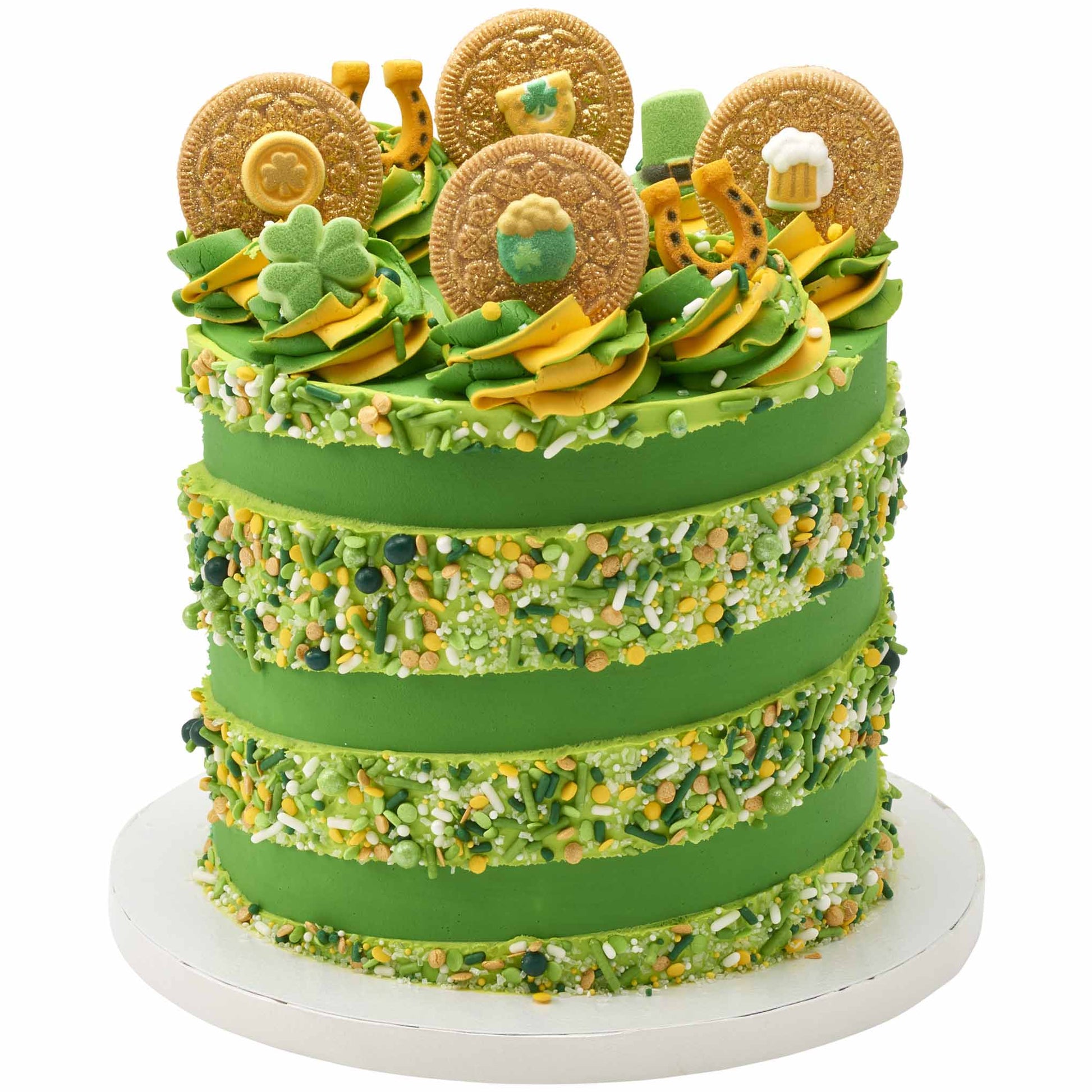 Green frosted layer cake decorated with a thick band of mixed green, yellow, and white sprinkles, topped with St. Patrick’s Day themed decorations including shamrocks and gold coin toppers.