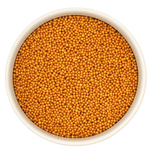 Top-down view of a white bowl filled with shimmer gold non-pareils, showing tiny round metallic sprinkle beads in a rich golden yellow shade.